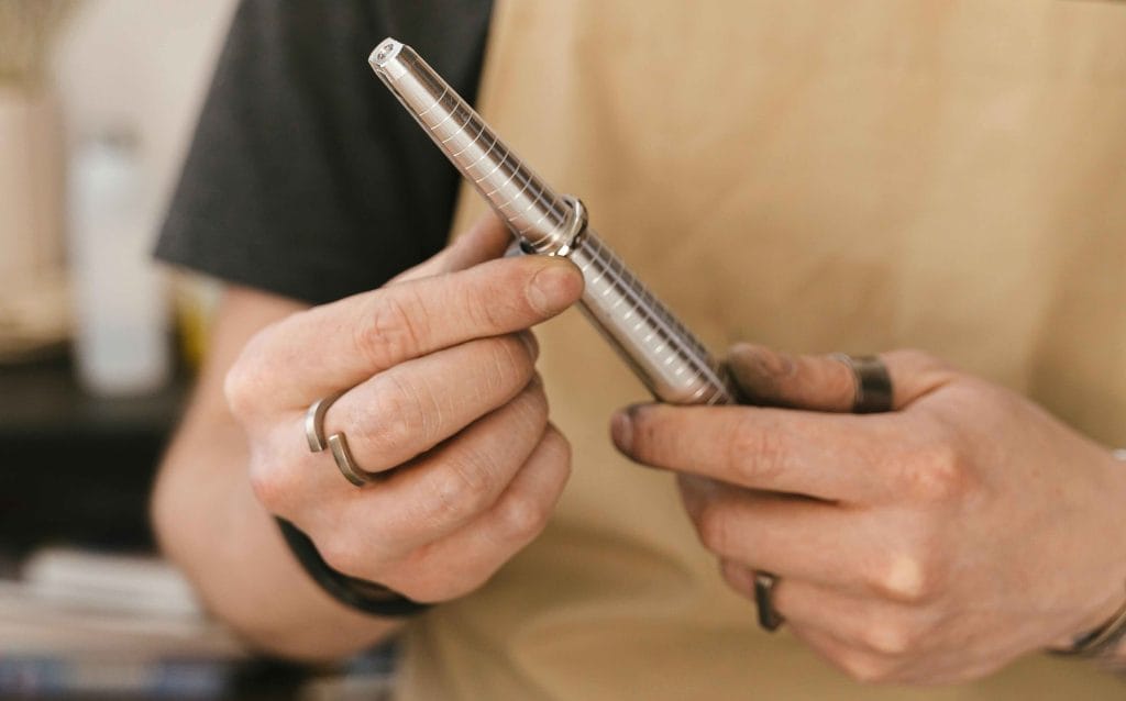 Hands using a ring sizer beside sketches and notes at a jewellery desk