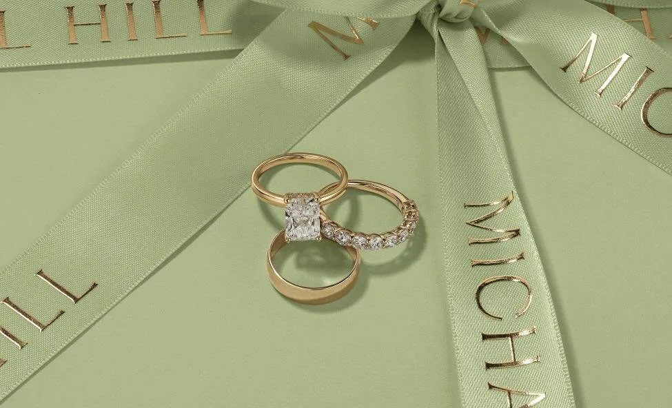 Luxurious gold rings with diamonds on a pastel green gift box.