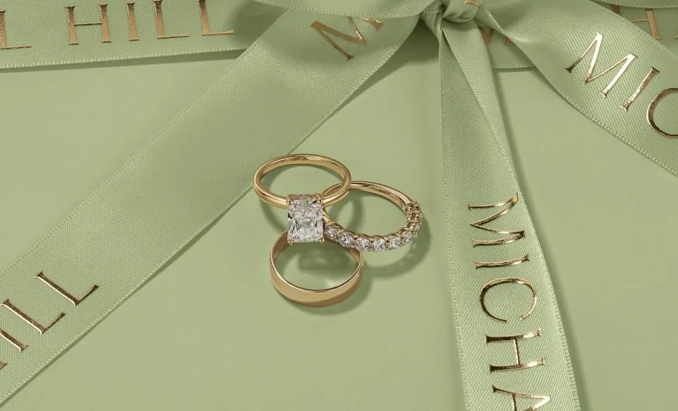 Luxurious gold rings with diamonds on a pastel green gift box.