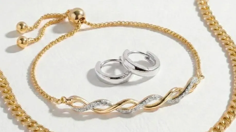 Gold and silver jewelry featuring intertwined chain necklace and matching hoop earrings.